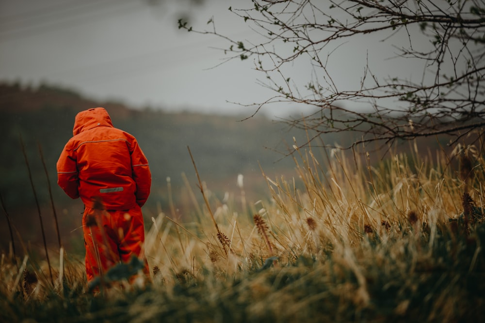 boy wearing orange hooded jacket on grass during day