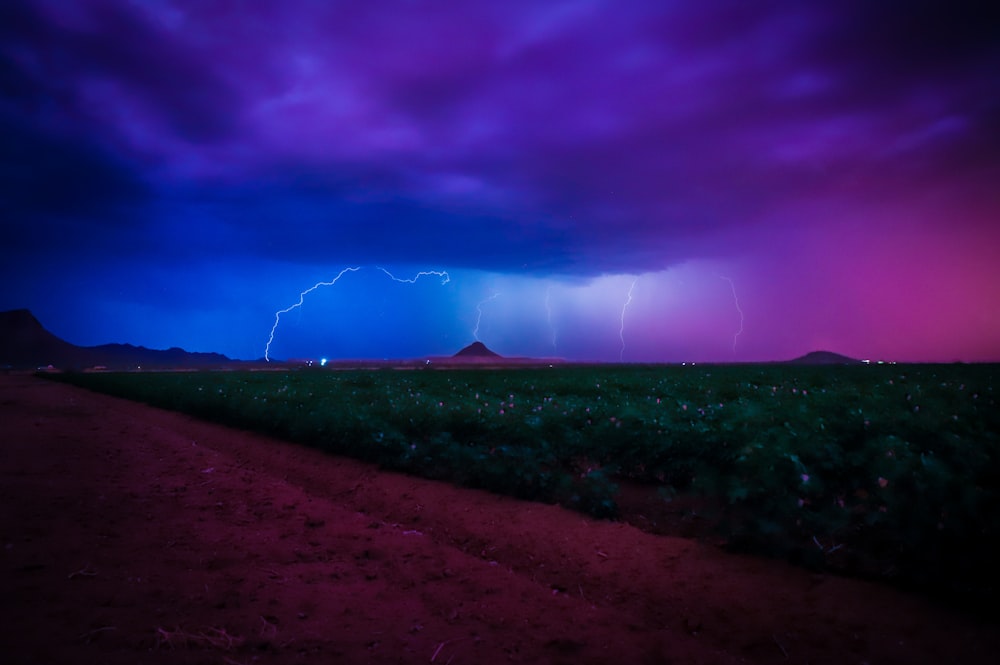 a purple and blue sky with lightning in the distance
