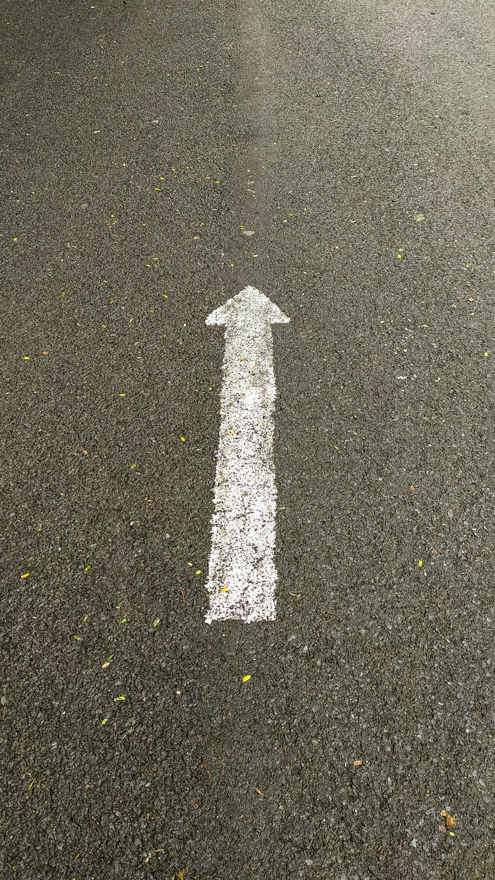 a white arrow painted on the asphalt of a street