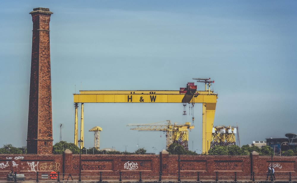 a large yellow crane sitting on top of a brick wall