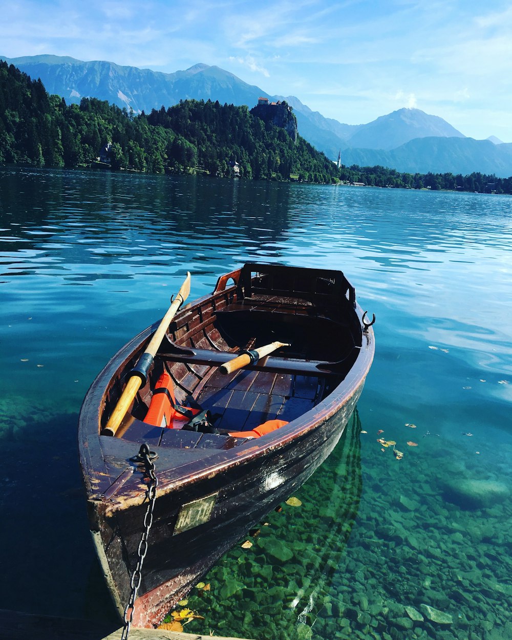 brown wooden boat on body of water near land during daytime