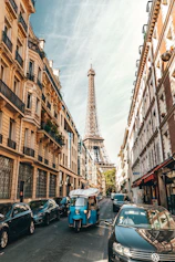 different vehicles parking near building viewing Eiffel Tower in Paris under white skies during daytime