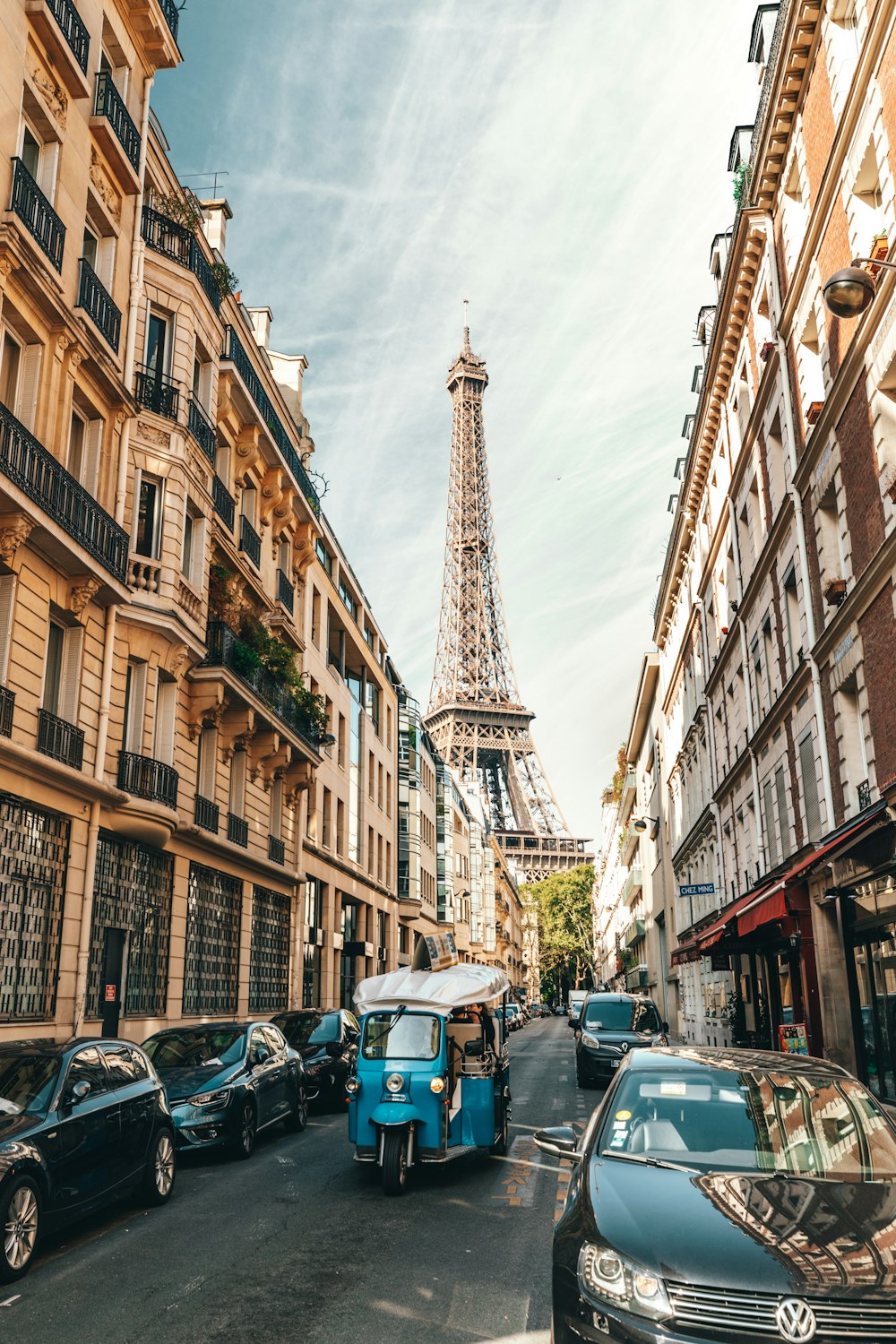 different vehicles parking near building viewing Eiffel Tower in Paris under white skies during daytime