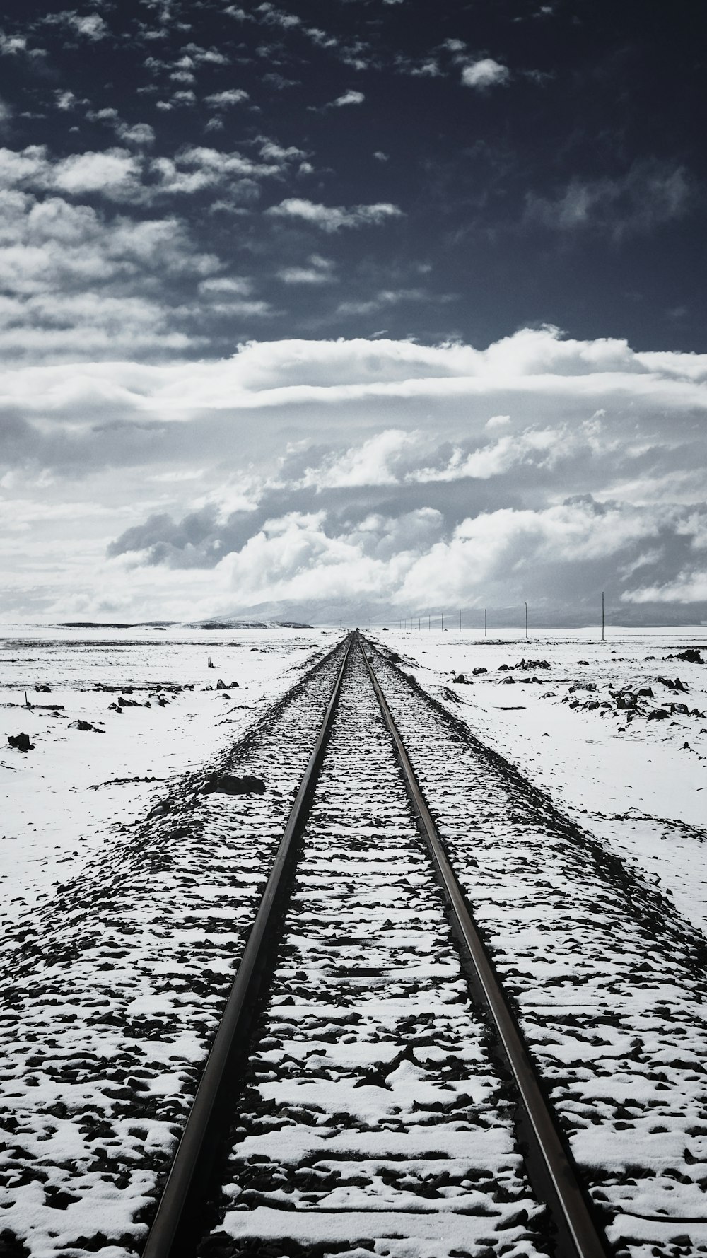 trilho de trem coberto de neve sob céu nublado