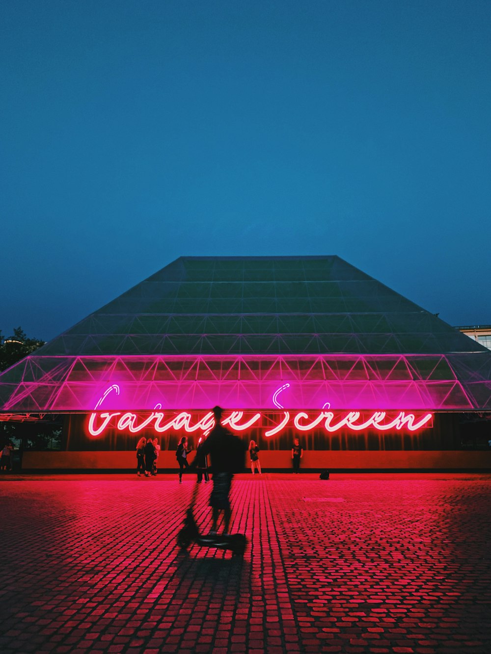 a man riding a scooter in front of a neon sign