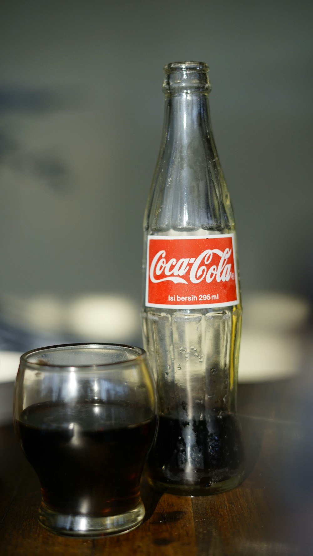 Coca-Cola-Limonadenflasche neben Trinkglas