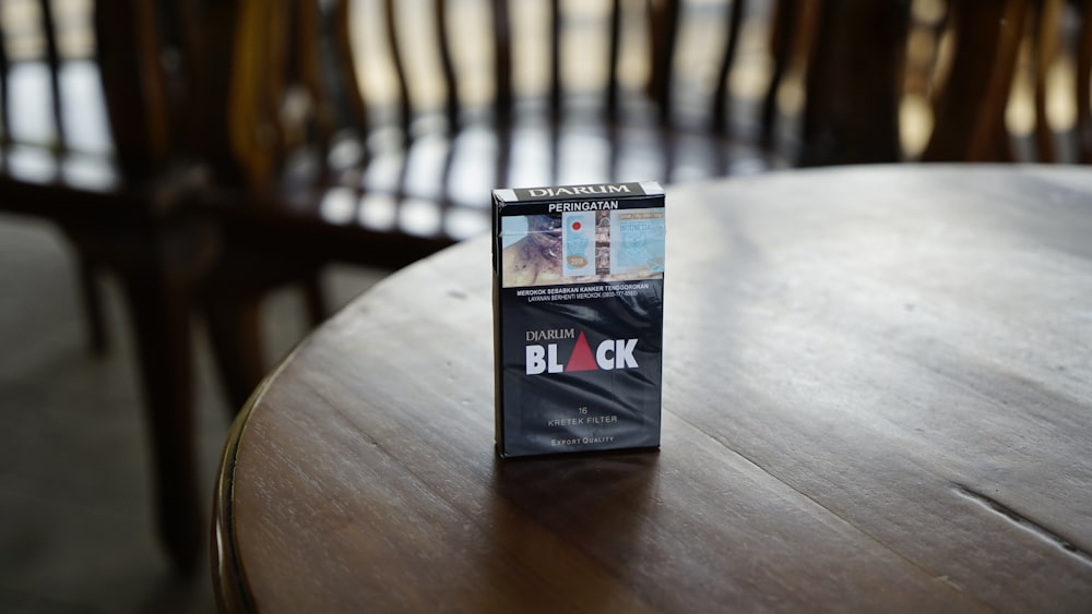 Black cigarette box on top of brown wooden table