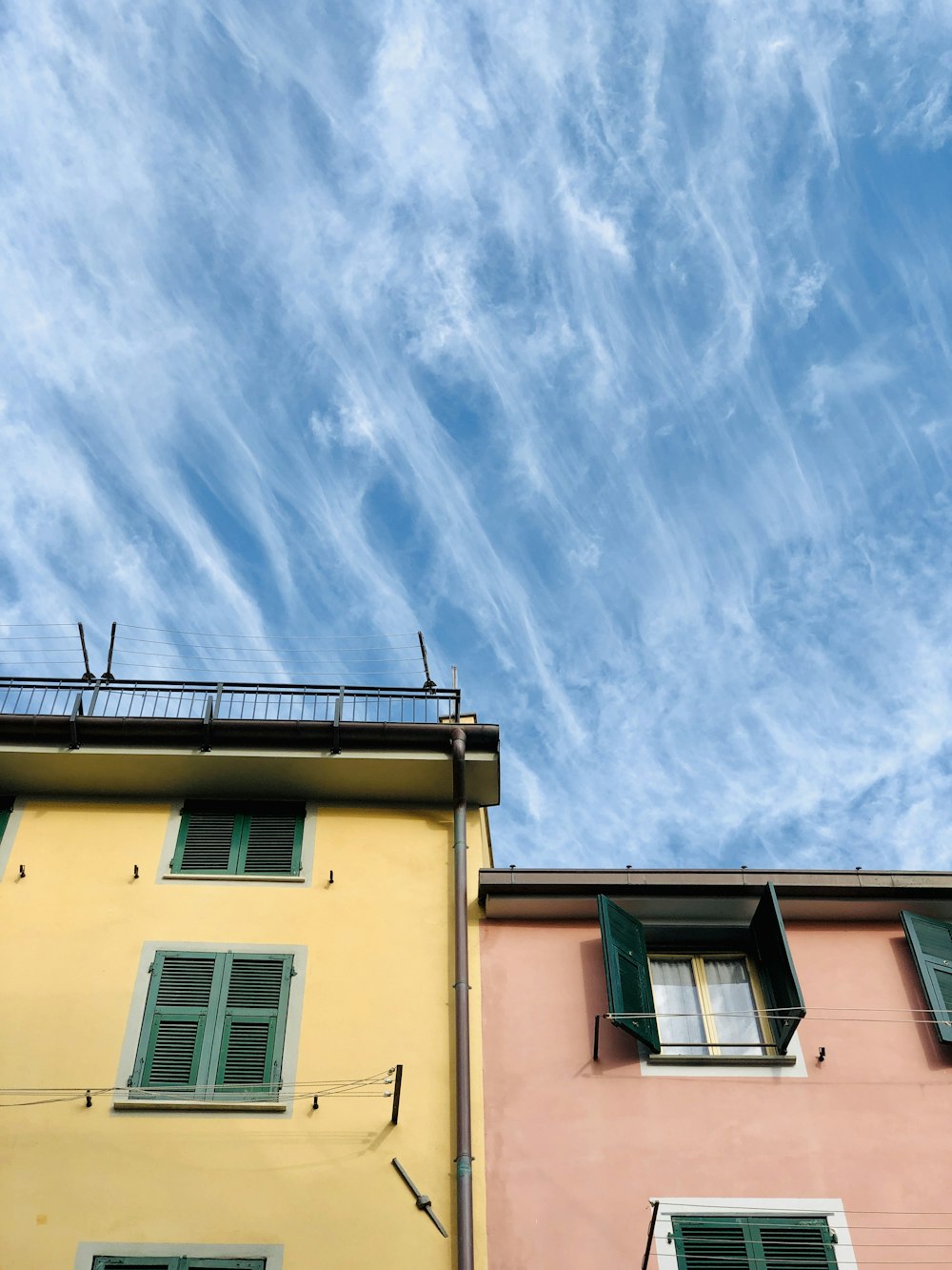 yellow and pink painted concrete houses under blue and white skies during daytime