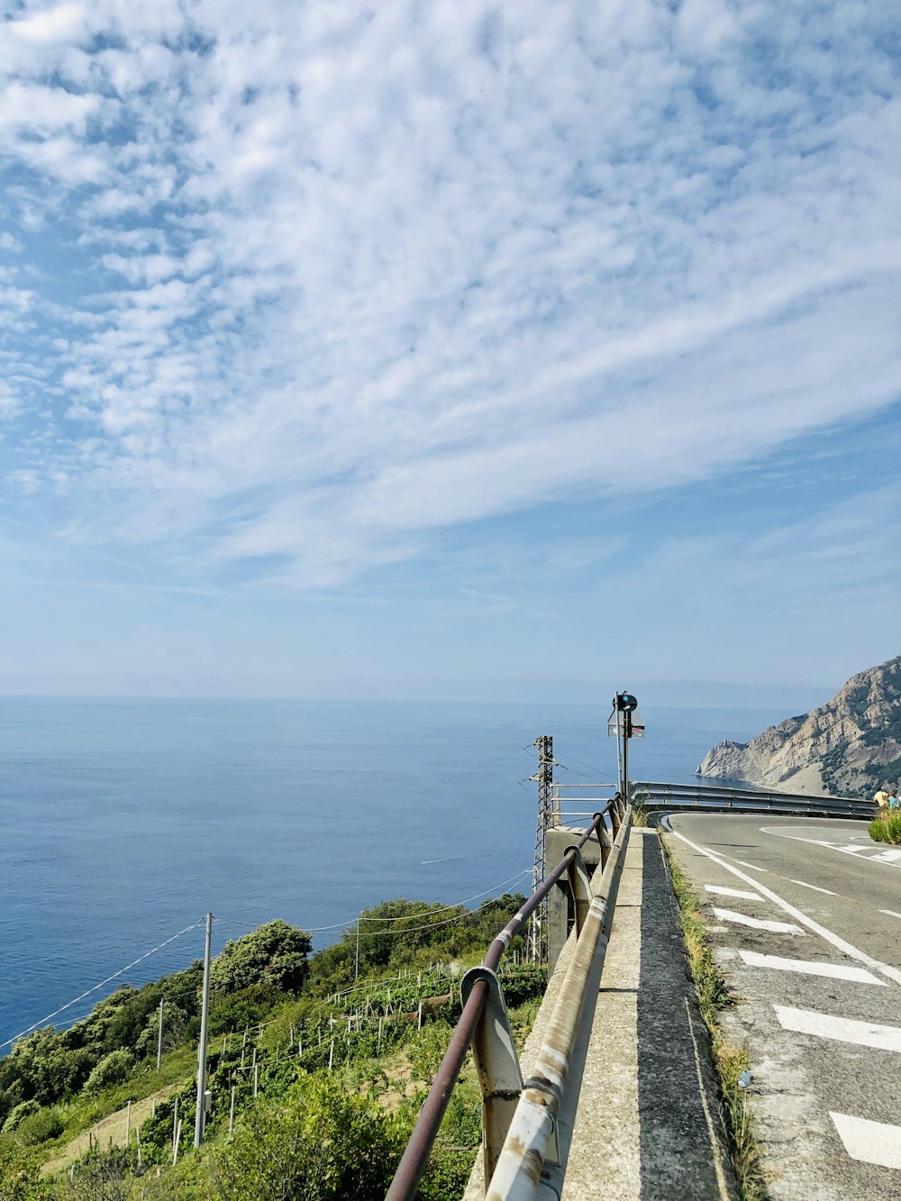 Route grise incurvée près de la mer par temps nuageux