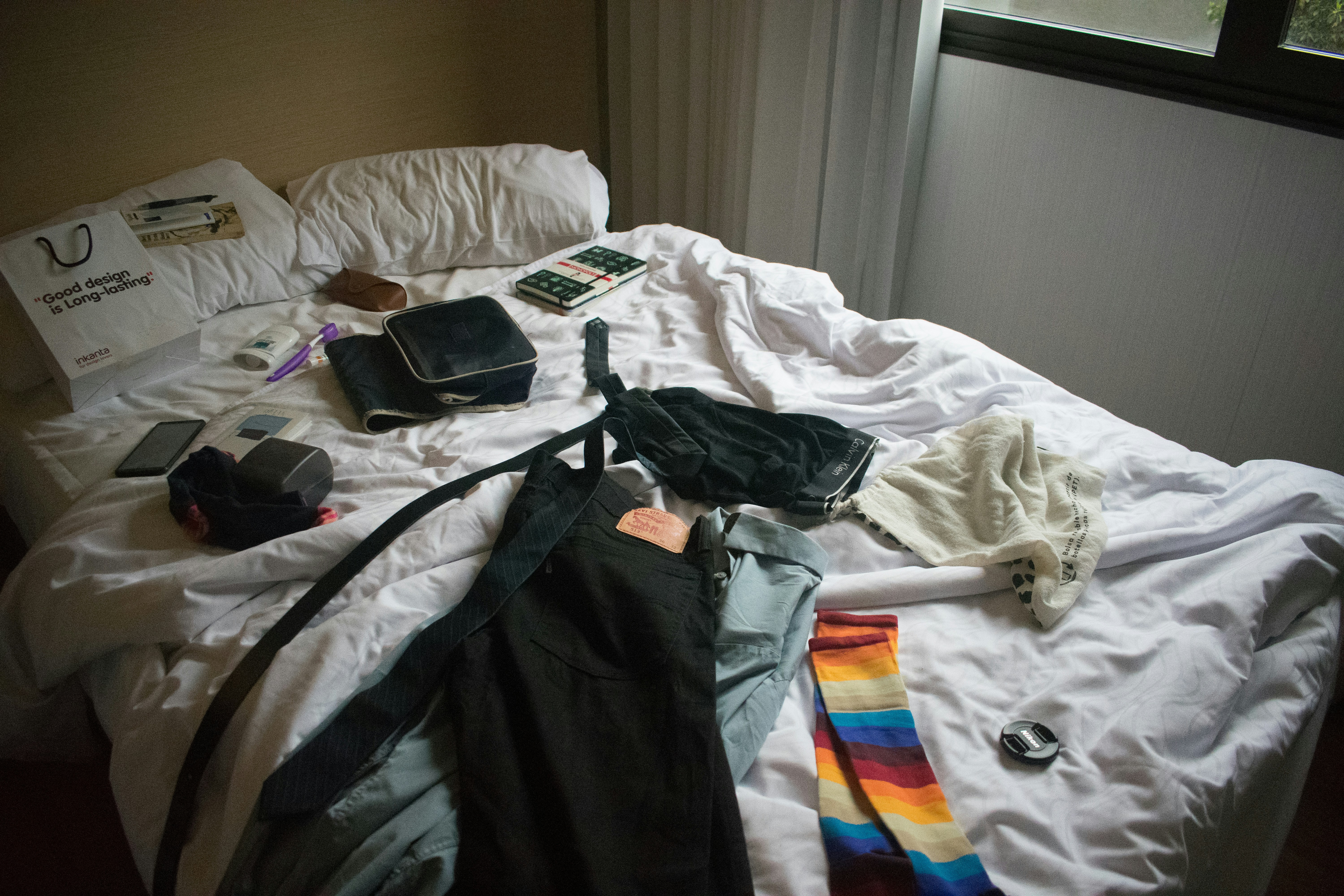 two blue and black jeans on bed