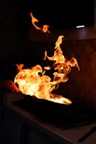 A vibrant kitchen scene with the Flammaease brush beside a sizzling pan of vegetables being basted.