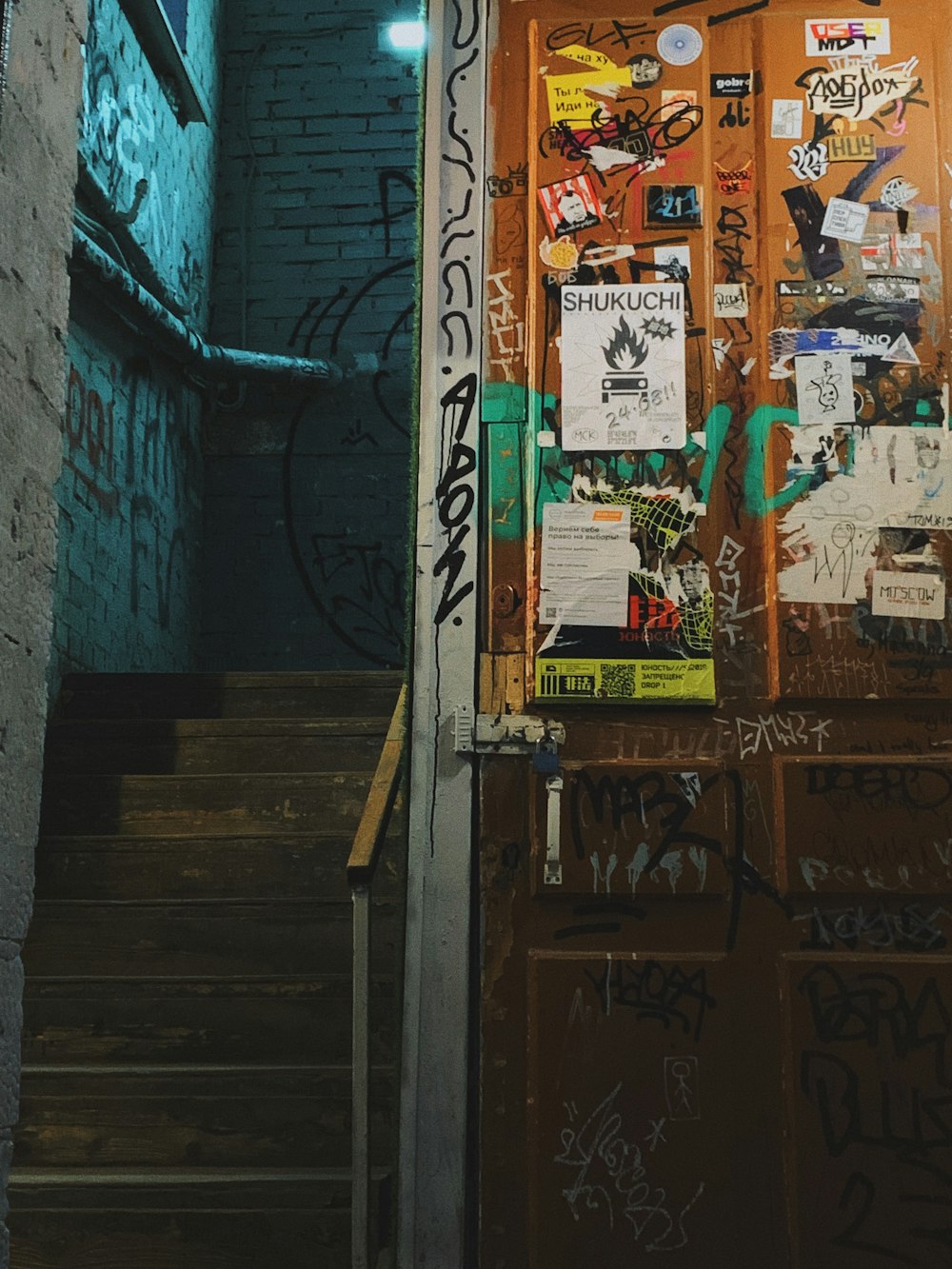 Una puerta cubierta de graffiti junto a un conjunto de escaleras