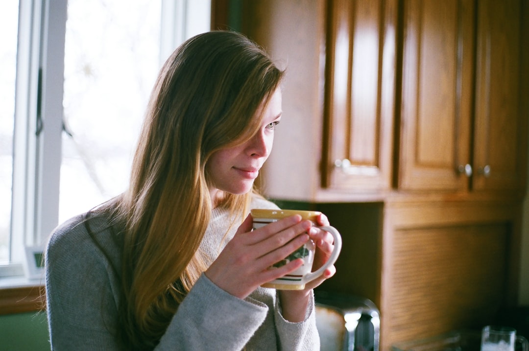 woman in gray long-sleeved top holding mug with both hands