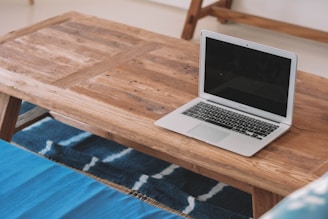 A solid wood coffee table with natural grain patterns sitting atop a textured rug.