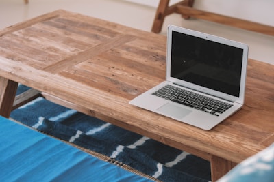 A solid wood coffee table with natural grain patterns sitting atop a textured rug.