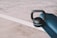 A black kettlebell rests next to a rolled-up blue yoga mat on a textured concrete floor with a white line in the background.