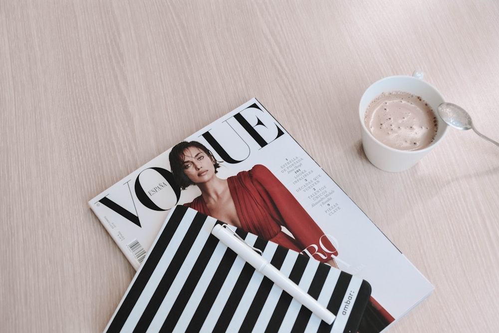stylo à capuchon blanc sur le dessus du magazine Vogue à côté d’une tasse de café