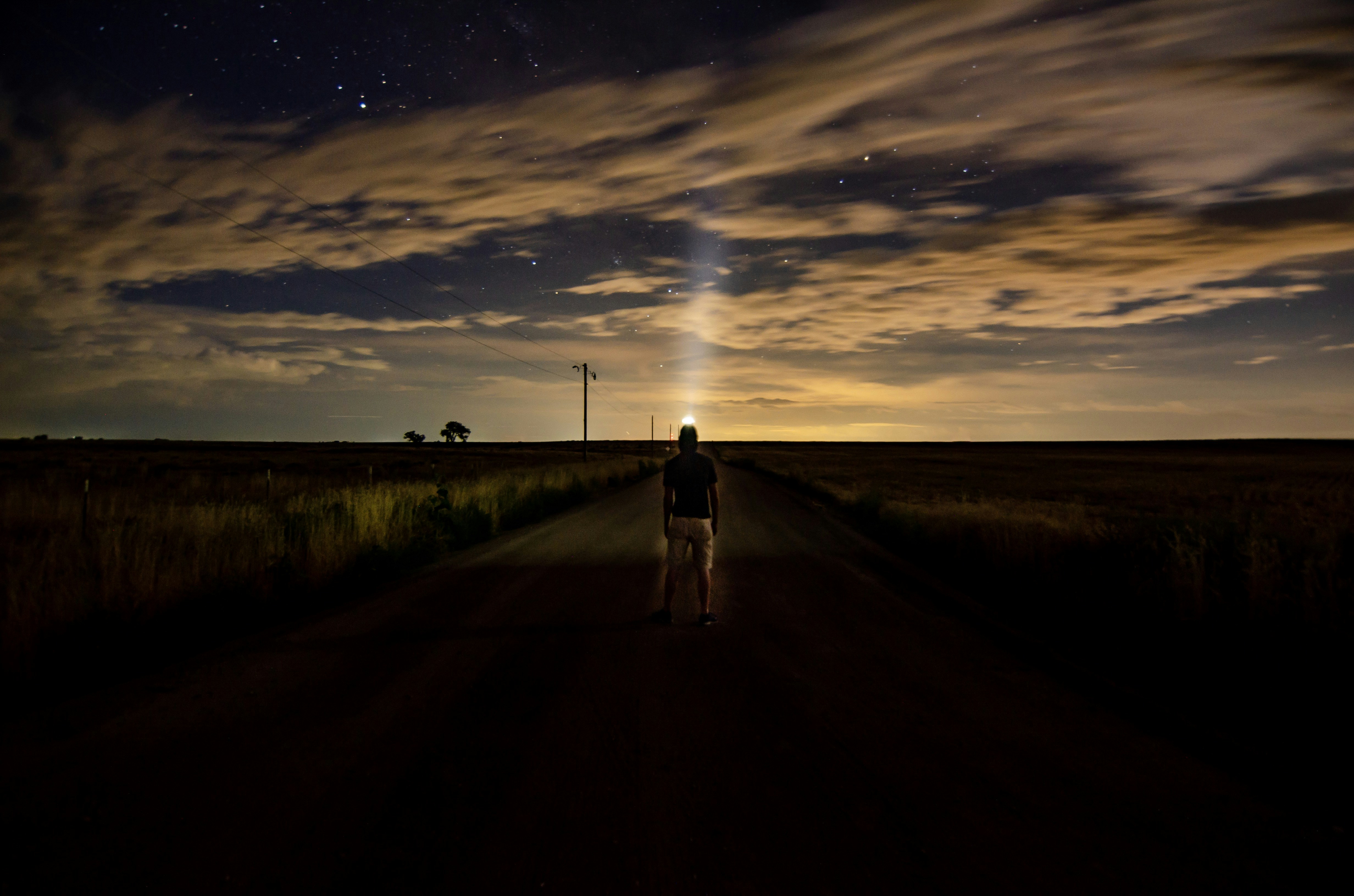 silhouette of person walking on road under cloudy sky during daytime