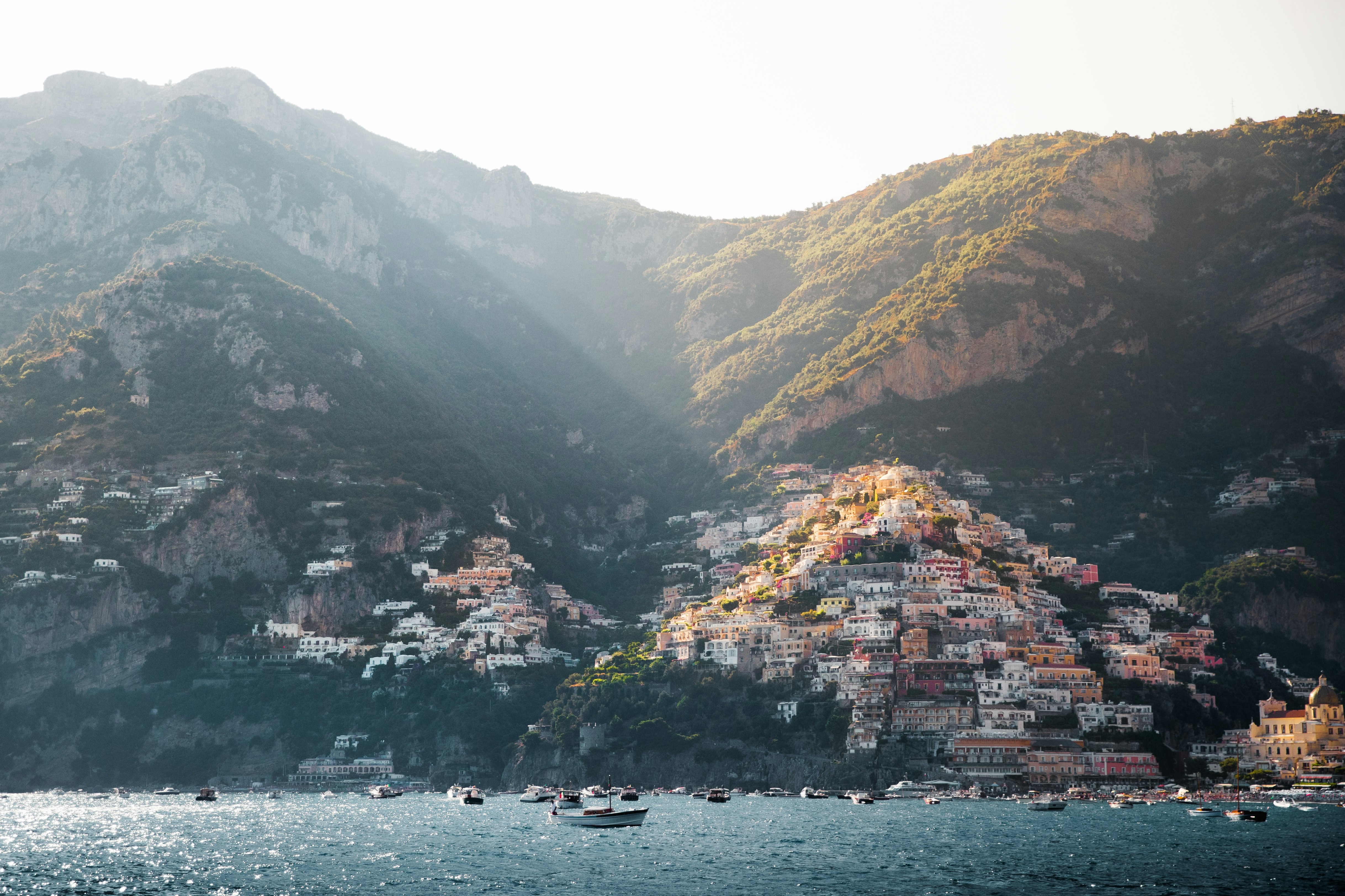 boat in body of water near mountain and building during daytime