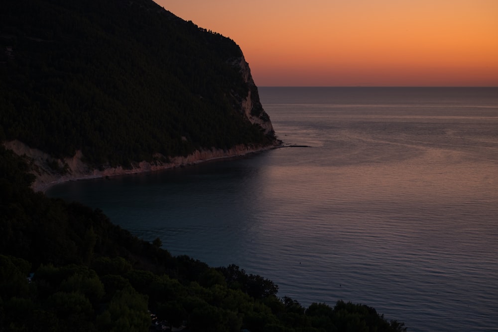 silhouette of mountain cliff beside seashore