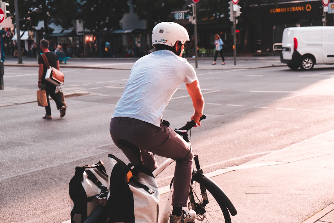 man wearing white shirt riding bicycle during daytime