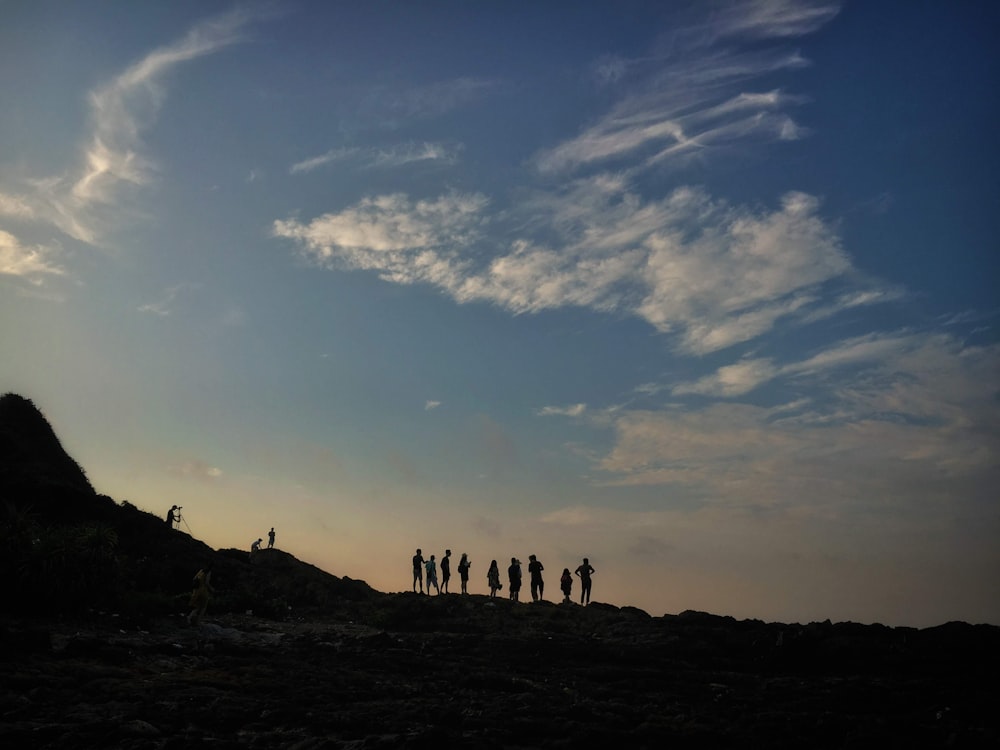 silhouette of people hiking on slope