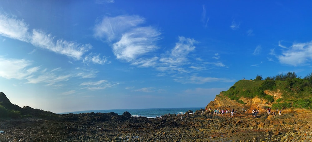 a group of people standing on top of a rocky beach