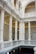 Elegant interior featuring classical architectural elements such as tall white columns, ornate moldings, and intricate railings. The space is well-lit, highlighting the detailed craftsmanship and symmetry of the design.