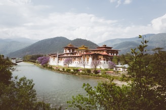 A serene Himalayan valley with a traditional Bhutanese monastery perched on a cliffside at sunrise.