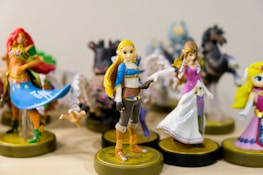 A collection of detailed and colorful figurines, primarily featuring characters in vibrant costumes. The central figure wears a blue top with a brown belt and boots, flanked by other characters in various striking outfits, all displayed on round bases.