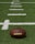 A close-up of a football resting on a grass field.