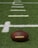 A close-up of a football resting on a grass field.