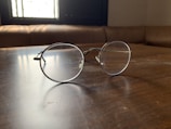Close-up of stylish round eyeglass frames on wooden table with natural light.