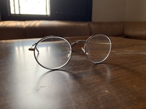 Close-up of stylish eyeglasses resting on a wooden table with soft natural light.