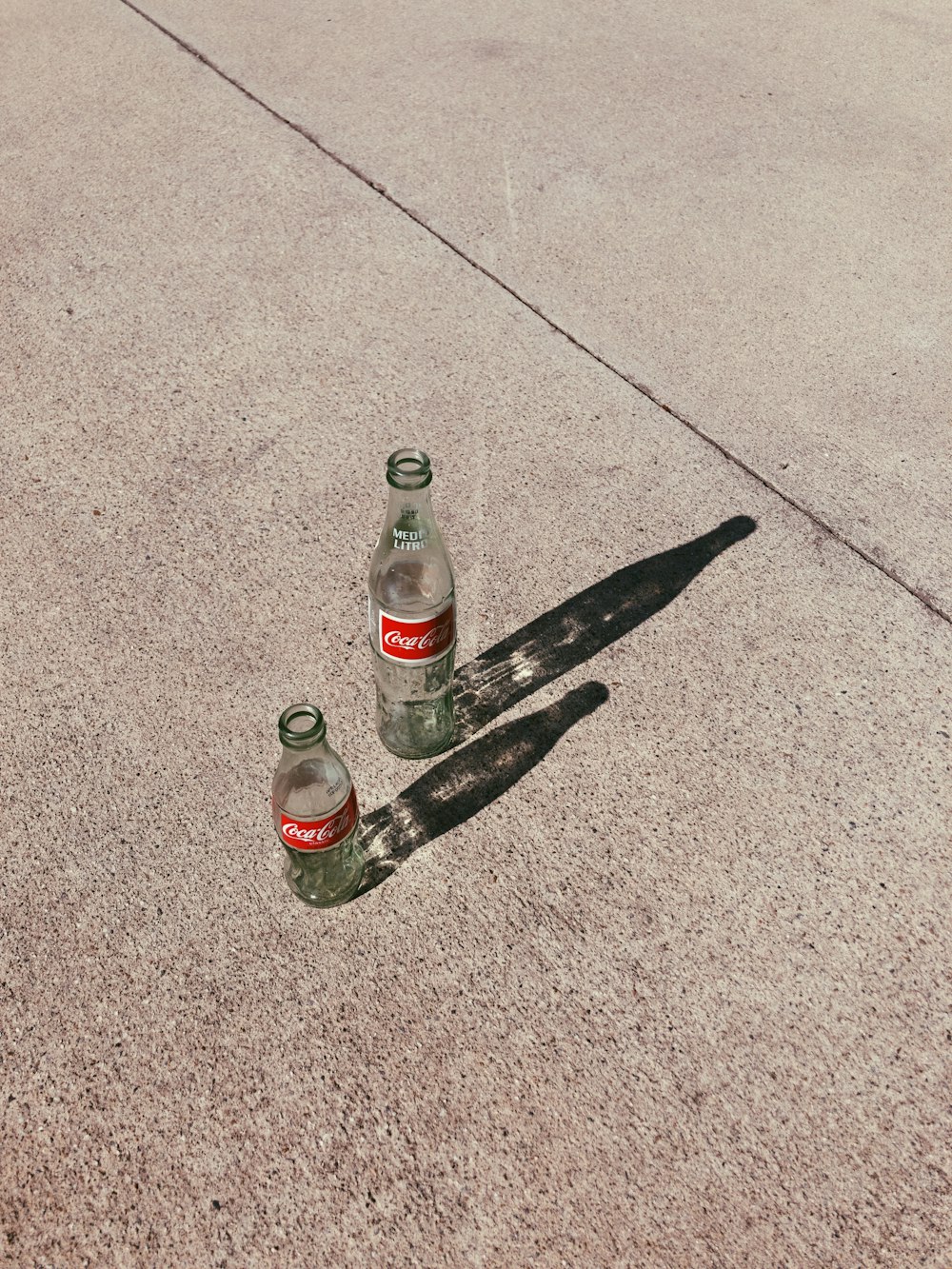 two empty glass bottles on pavement