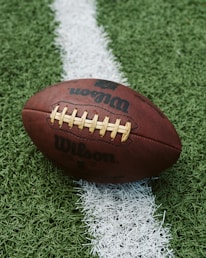 A close-up of a football resting on the grass, symbolizing the game.