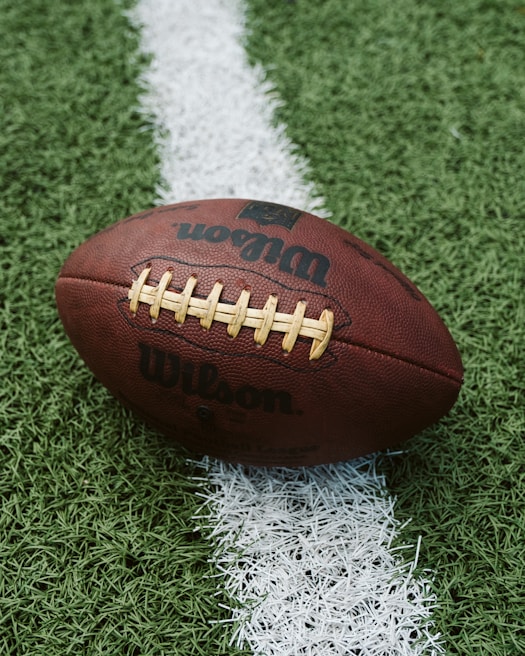 A close-up of a football resting on a grassy field.