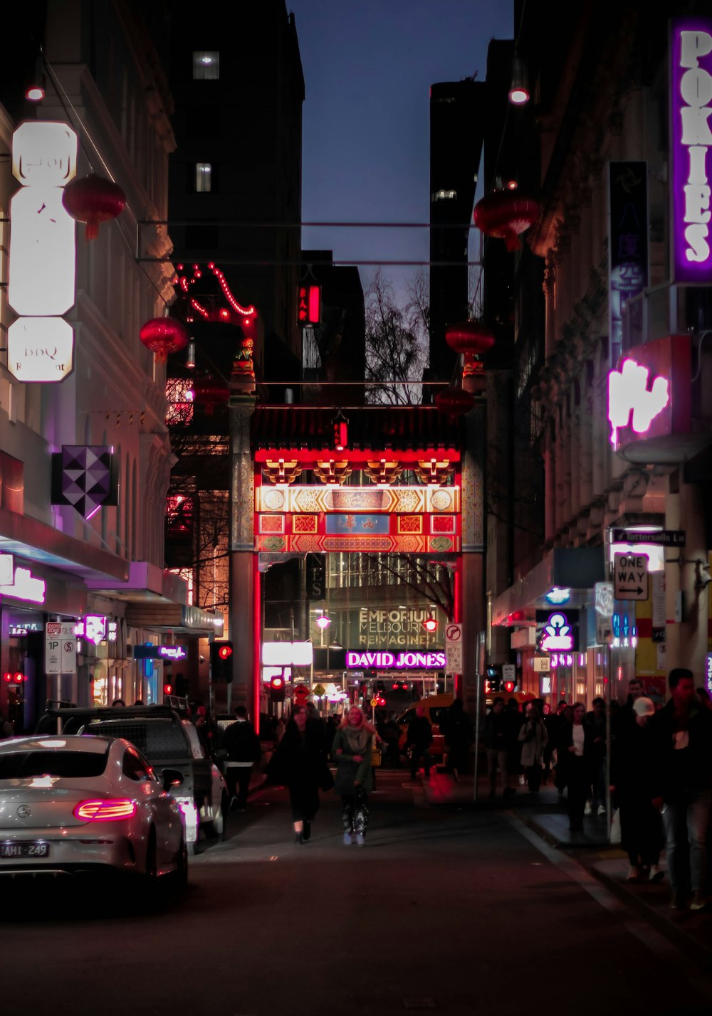 people walking near cars between buildings