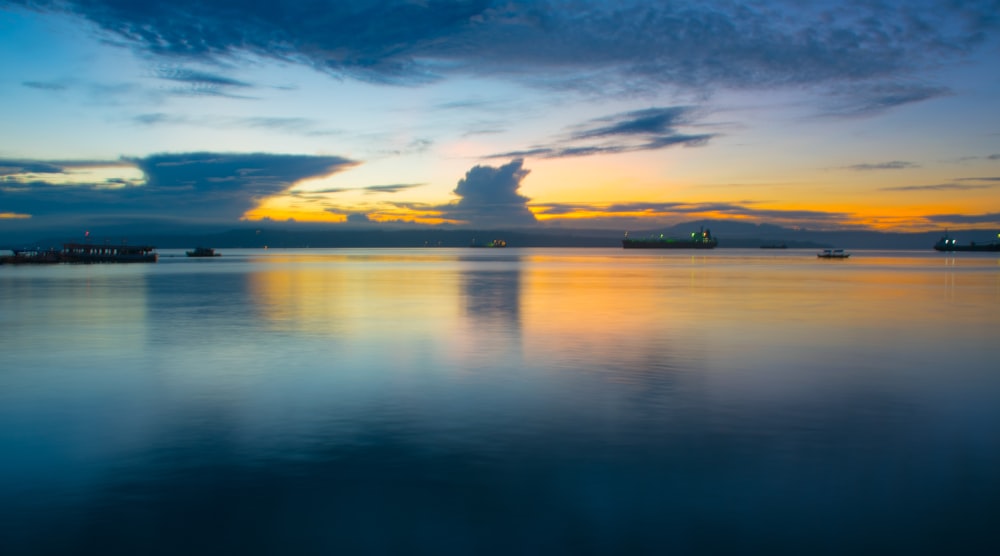 body of water under blue and brown sky at golden hour