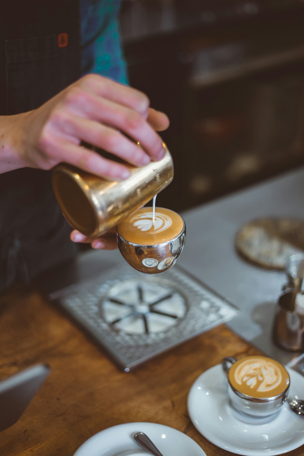 person pouring milk on latte