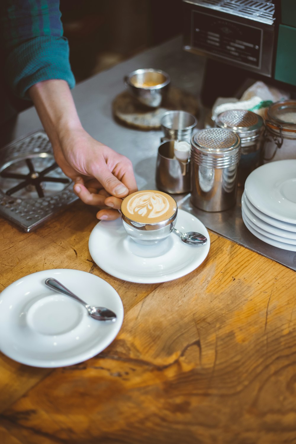 a person putting a cup of coffee on a plate