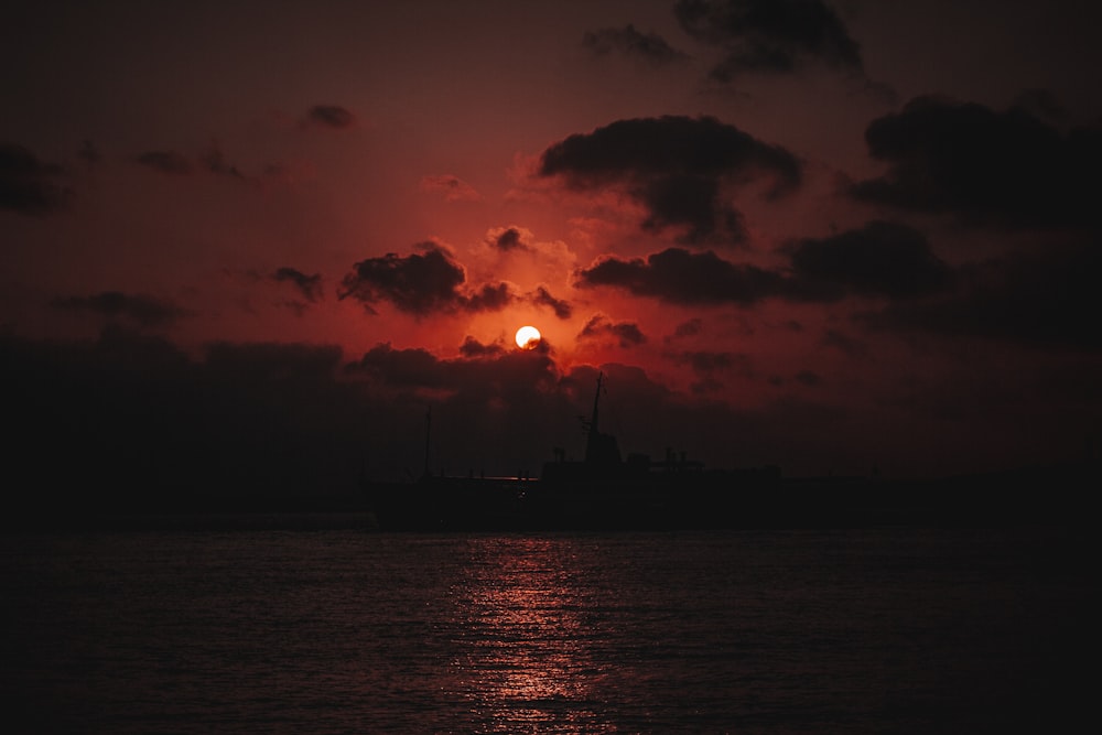 silhouette of sea under red and black skies