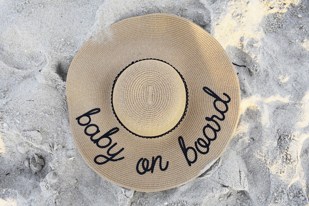 un cappello che dice spiaggia a bordo sulla sabbia