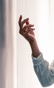 Close-up of hands expressing emotion through delicate, poetic gestures in natural light.
