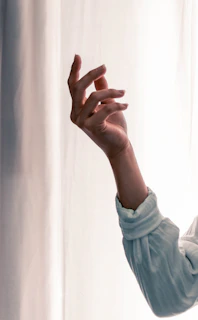 A gentle, artistic shot of a model’s hand tracing soft lines on her body, emphasizing subtle textures and light.
