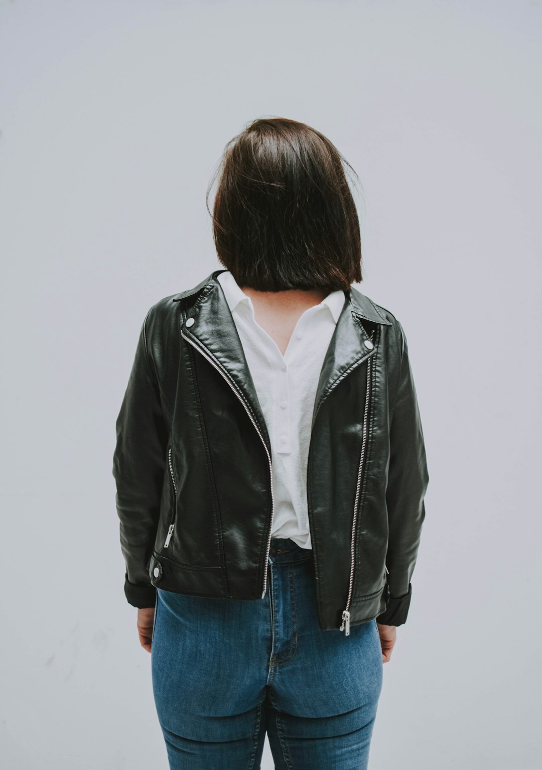 person wears black leather zip-up jacket close-up photography