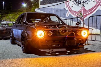 black muscle car with headlights turned on