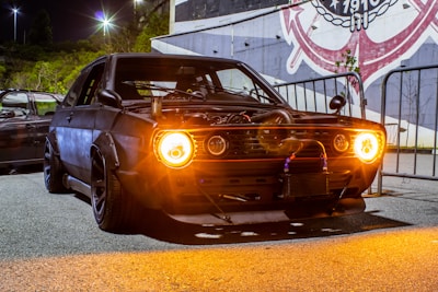 black muscle car with headlights turned on