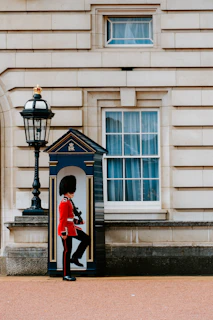 man wearing red and black top standing in front of white door England