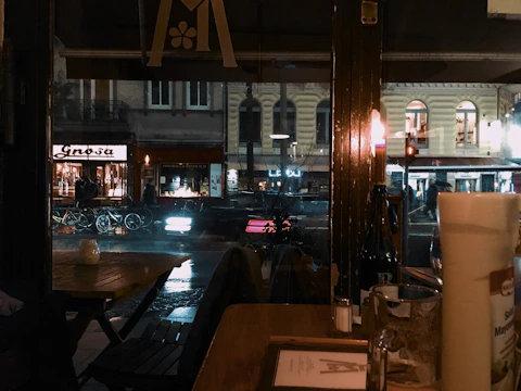 A rainy Seattle street scene viewed through a fogged café window with amber lights glowing warmly inside.